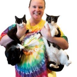 Happy volunteer holding 2 cats.